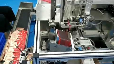 video of automatic facial mask folding machine feeding mask on conveyor by workers
