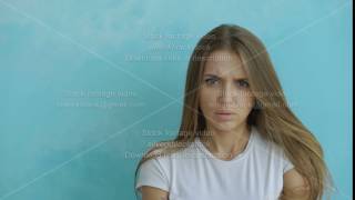 Portrait of angry young woman looking into camera nervous on blue background