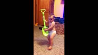 Cute baby playing guitar on a shovel