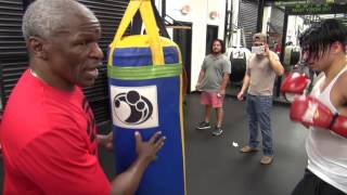 Floyd Mayweather instructing Aldo Uribe on the heavy bag inside Mayweather Boxing Club