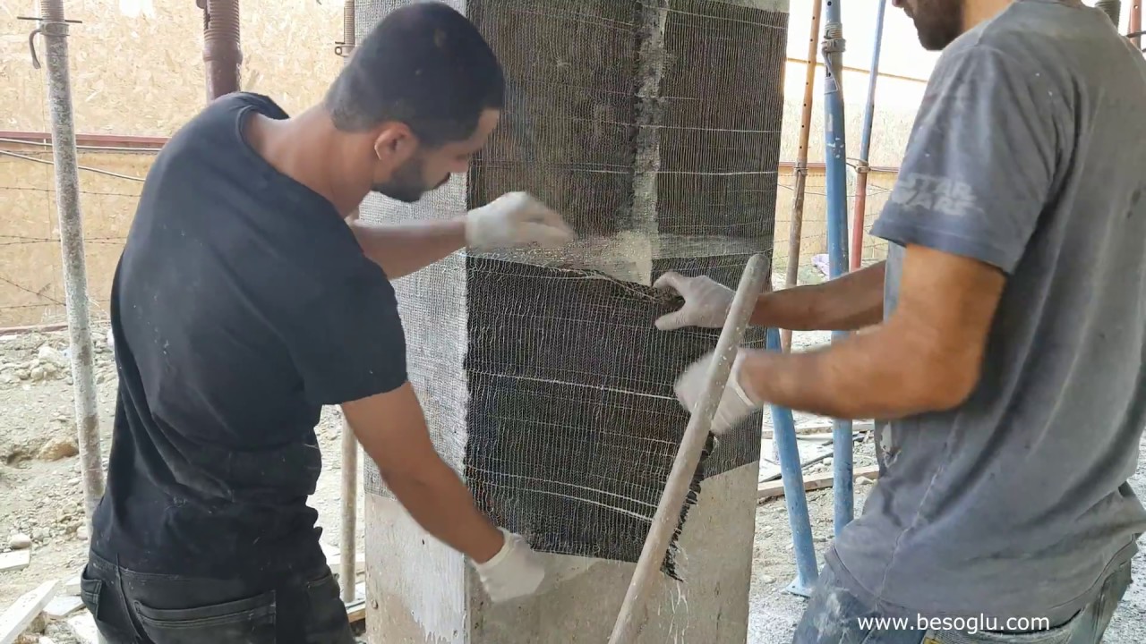 İki usta, iskele arasındaki betonarme bir kolonu karbon lif kumaşla sarıyor