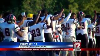 Local high school football players raise fists during national anthem