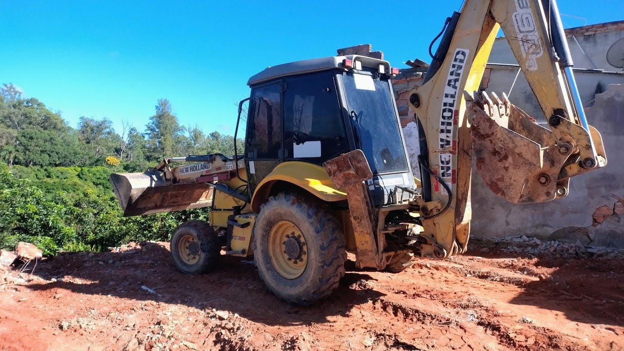 RETROESCAVADEIRA NEW HOLLAND B90B demolindo barracão, dia de limpeza.