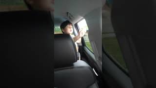 Boy looks out the window in back seat of car and says good morning mother f mf