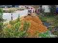 Full action  power stronger bulldozer spreading stone into water with dump trucks filling land