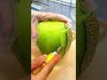 Peeling a fresh green melon with a sharp knife on a board for healthy food preparation