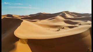 A golden sand desert where the sand dunes are moving and rolling smoothly like ocean waves.