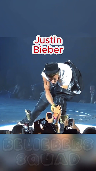 Justin Bieber is helped by fans in the front row to take off his jacket