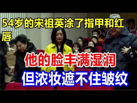 54岁的宋祖英涂了指甲和红唇。他的脸丰满湿润，但浓妆遮不住皱纹