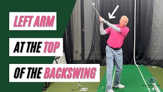 Where should your left arm be at the top of the backswing?