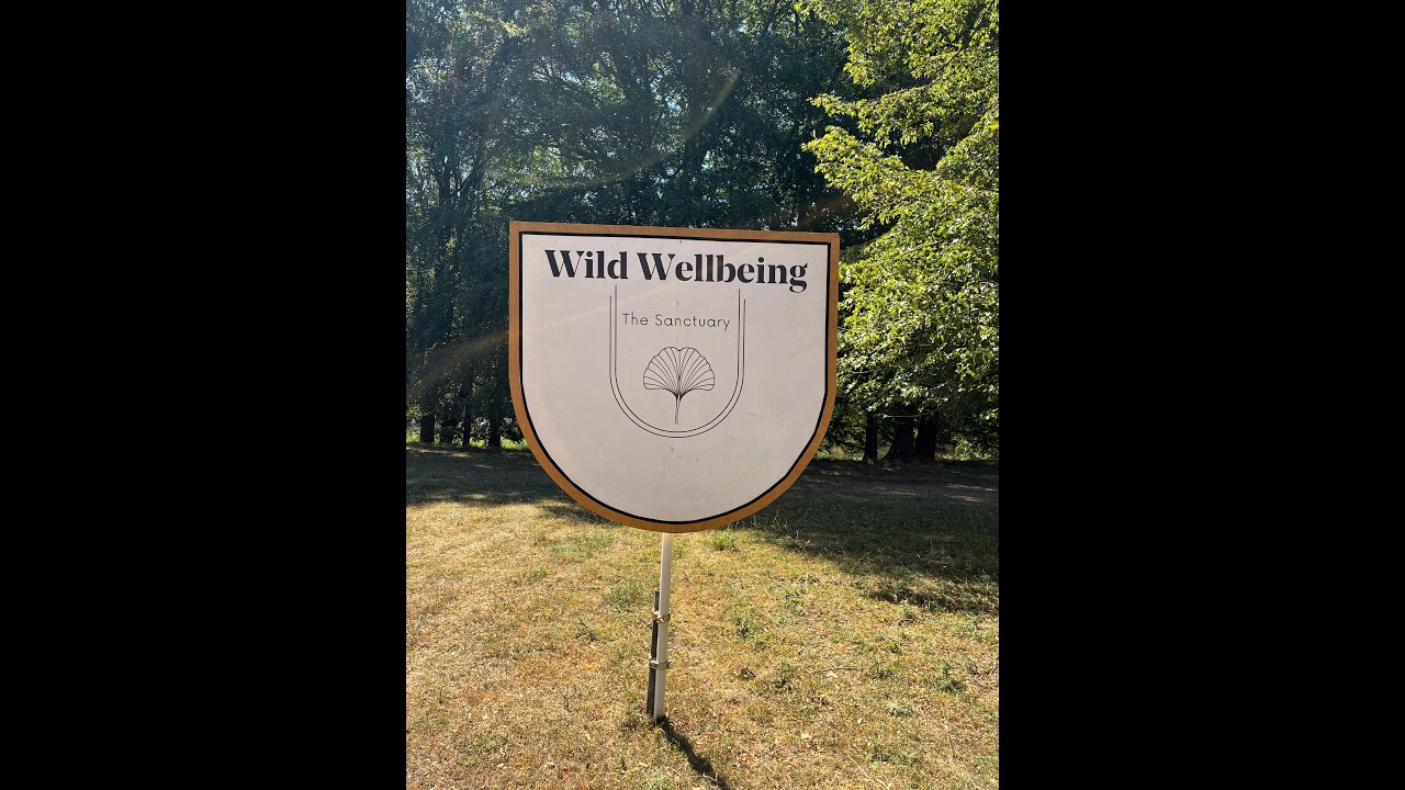 Wild Wellbeing sign among the trees at Wilderness Festival 2026