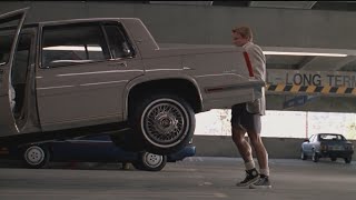 Арнольд Шварценеггер поднимает зад машины, чтобы отключить сигнализацию.  Близнецы (фильм 1988)