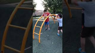 Boy pulls himself up on monkey bars at playground then bumps chin on pole