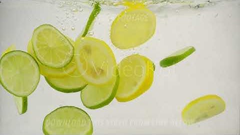 Slices of citrus lime and lemon fall into the water with splashes and bubbles, slow motion close-up