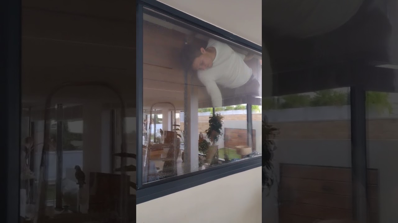 Operario limpiando un cristal con muy poco espacio para maniobrar
