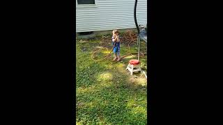 Girl sprays herself on face with water hose