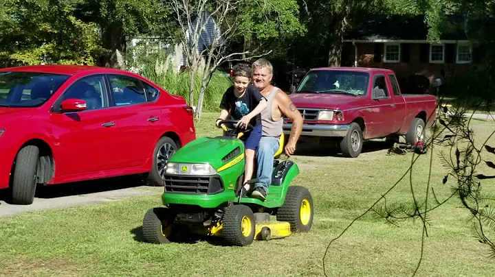 A neighbor  teaches a kid to drive his mower