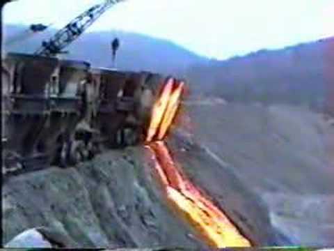 A PBNE switcher takes slag cars to the slag dump where they are dumped by a crane.