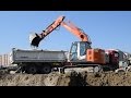 Hitachi zaxis 135us excavator digging and loading dirt to scania r420 cb dump truck with trailer