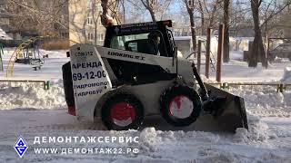 Уборка снега во дворе дома маленьким трактором.