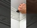 Lagu A hand is smoothing caulk into the corner of decorative crown molding