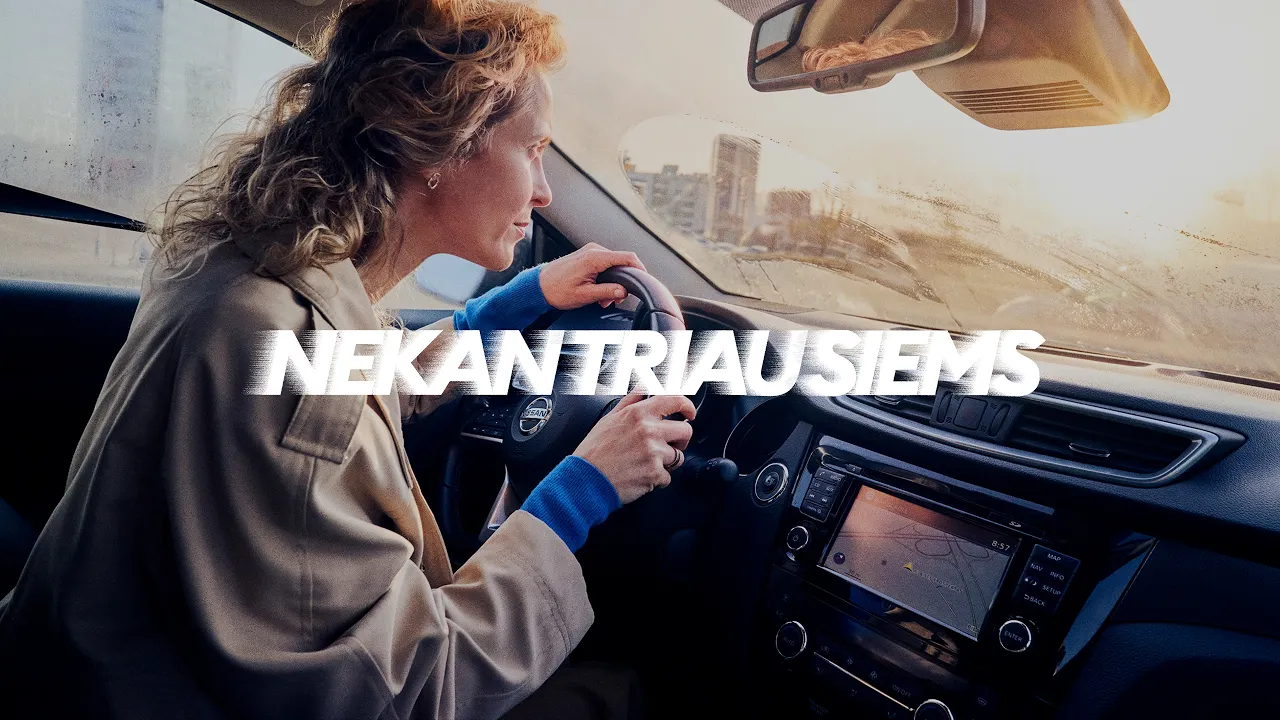 The video opens with a woman driving a car on a misty or rainy day, her windshield wipers are on. She looks slightly…