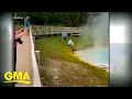Tourist touches hot spring with hand at Yellowstone GMA
