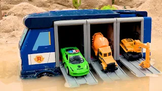 Hormigonera, excavadora, coche de policía en el enorme camión