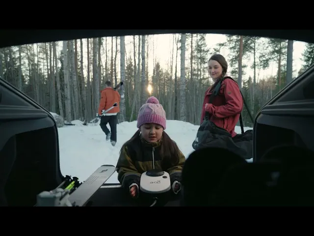 Семейство в зимна обстановка, момиче с играчка в колата, снежна гора на заден план.