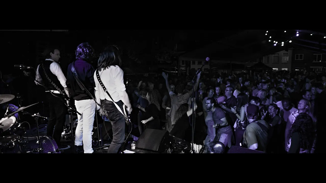 Cinematic close-up of an electric guitar being played on a dark stage with vibrant golden lighting
