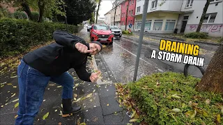 #079-1 Unclogging a storm drain on a parking space during rain in Germany