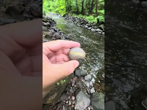 A quiet moment lifting a printed stone next to a flowing stream