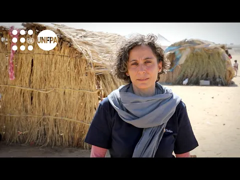 Fabrizia Falcione, UNFPA Sudan representative, is shown standing in front of two huts in the Goz Al Salam displacement camp in West Nile State, Sudan. 