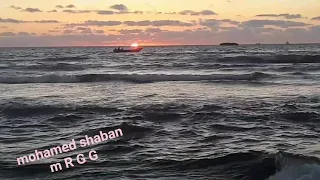 وقت غروب الشمس واقف علي البحر بعيد 