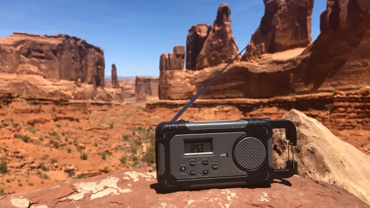 Liberty Band emergency weather radio with solar and hand-crank power sits on a rock in a desert canyon, highlighting its role as a rugged backup power supply in remote locations.