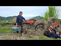 Girl repairs and restores a broken tractor in the middle of a field.