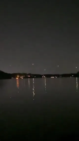 imagem mostra um cenário noturno sobre a água com vários pontos luminosos no horizonte. Não é possível confirmar pela imagem se ela foi realmente gravada na Noruega nem identificar a origem dos objetos luminosos apenas por este quadro. Eles podem ser luzes distantes, reflexos, drones, aeronaves ou outras fontes de iluminação.