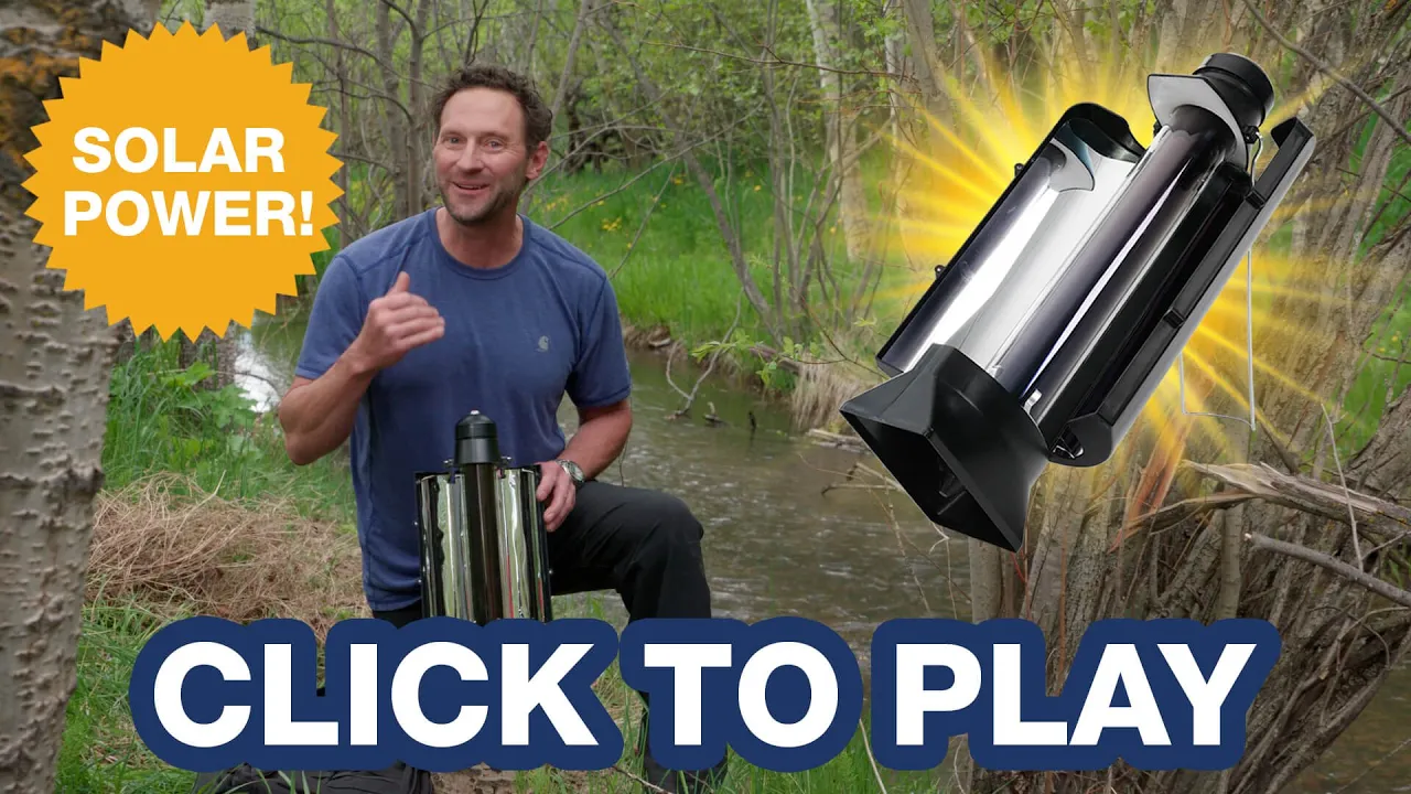 Man kneels by a creek demonstrating the 4Patriots Sun Kettle, a solar-powered water heater ideal for off-grid emergencies and outdoor survival.
