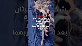 شاهد   شخصان يتشبثان بجذع شجرة وسط نهر بعد انقلاب قاربهما وانجرافه دندنها