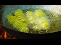 Spiral-cut fried potatoes cooked in a giant pan – traditional cooking over a wood fire.