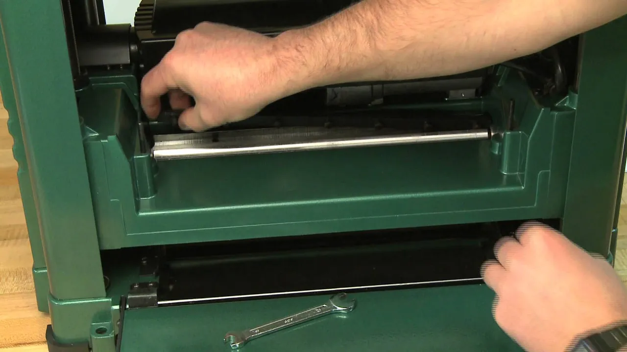Hands installing a knife in a portable planer cutterhead