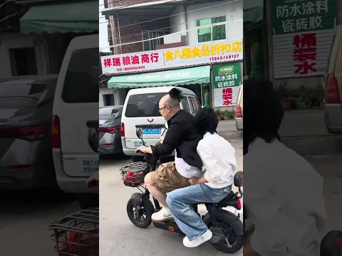Man struggles to keep his wig in place while riding an e-bike in Fujian, China