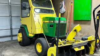 1992 John Deere 318 with cab taking a ride in a downpour