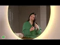Charming mature Asian woman combing long brown hair with brush in bathroom