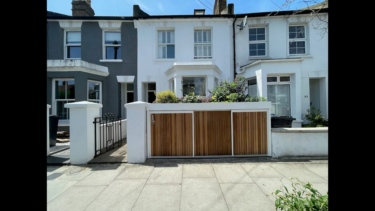 Video showing a London front garden wall replacement with bespoke bike and bin store. Demonstrates sliding street-side doors opening for bike access, bin storage access, and taking a bin out onto the pavement.
