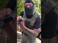 shows masked federal agent pointing a gun at woman in her car